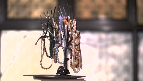 Many-colored-gem-beads-pincer-on-black-gazelle-plastic-model-turntable-slow-motion