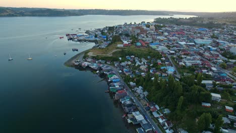 Panoramic-Aerial-Drone-Sunset-above-Pedro-Montt-Palafitos-Bay-in-Castro,-Sunset,-pristine-water-with-Patagonian-Island-Town