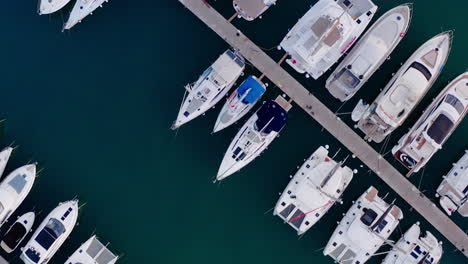 Top-down-view-of-a-crowded-harbour-on-the-Adriatic-Sea-in-Croatia,-boats-parking,-sailboats,-speedboats,-motorboats,-dock,-dark-blue-waters,-pier,-jetty,-tourism,-travel,-summer-vacation,-water-sports