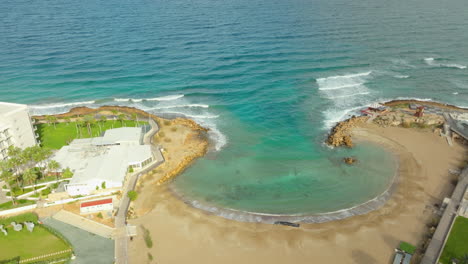 Playa-De-Agia-Triada-Con-Aguas-Cristalinas-De-La-Bahía-Del-Mar-En-Chipre-En-Un-Día-Soleado-Desde-Arriba