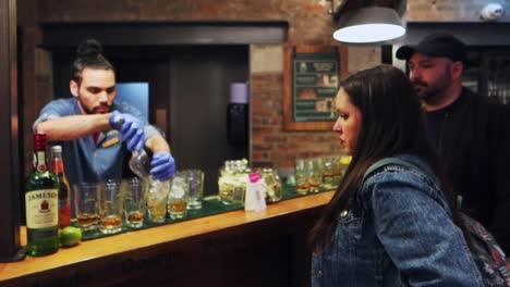 Woman-waiting-for-whiskey-glass-with-man-behind,-bartender-at-counter