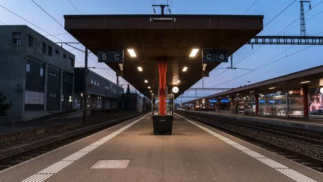 Commuters-gather-at-evening-train-station-platform-during-rush-hour,-day-to-night-timelapse,-Switzerland