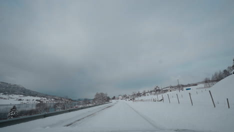 POV-drive-through-Norway's-western-fjord-on-a-snowy-winter-day,-featuring-beautiful-snowy-mountains-and-roads