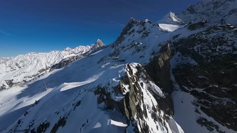 Vista-Aérea-Sobre-Una-Montaña-Nevada-En-Un-Día-Soleado-Con-Un-Cielo-Azul-Claro,-Cerca-De-La-Estación-De-Esquí-De-La-Región-De-Chamonix