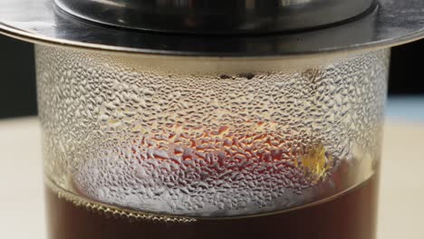 Nahaufnahme-Einer-Schwarzen-Kaffeekanne,-Die-In-Ein-Glas-Tropft,-Fallender-Tropfen-In-Zeitlupe