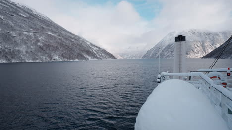 Slow-motion-POV-of-a-winter-ferry-boat-ride-in-Geirangerfjord-to-Geiranger,-Norway,-with-snowy-mountains-and-captivating-fjord-views