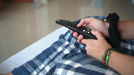 Hand-of-a-person-with-the-remote-control-of-the-tv-on-the-sofa-at-home