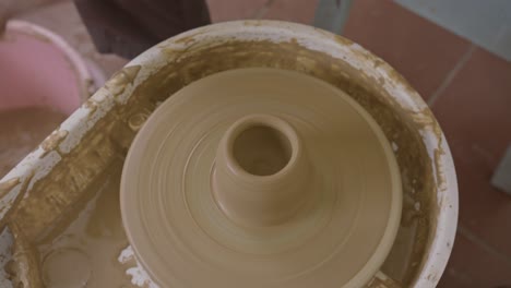 Close-up-of-hands-shaping-wet-clay-on-a-spinning-potter's-wheel,-craftsmanship-in-action