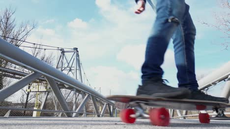 Older-man-in-jeans-and-red-cap-circling-on-a-longboard-on-the-sidewalk-with-an-old-factory-in-the-background