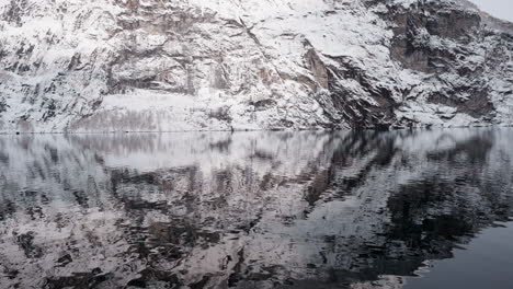 Slow-motion-POV-of-a-winter-ferry-boat-ride-in-Geirangerfjord-to-Geiranger,-Norway,-with-snowy-mountains-and-captivating-fjord-views