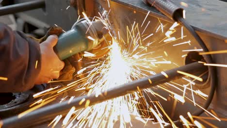 Close-up-of-a-worker-grinding-metal-with-sparks-flying,-in-natural-light