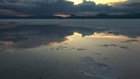 Aerial-of-the-salt-flats-with-the-water-reflection-of-the-sky-and-mountains-on-the-horizon