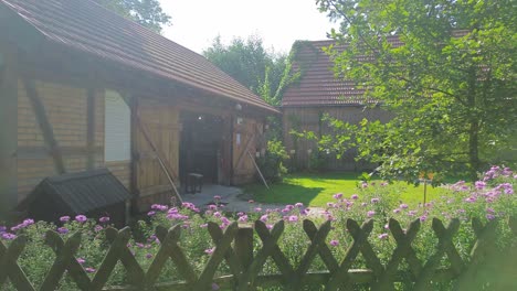 long-shot-slide-along-fence-with-flowers-old-building-dog-house-milk-can