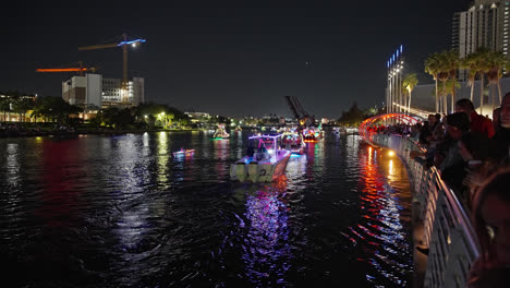 Gente-En-Riverwalk-Viendo-El-Desfile-De-Barcos-Iluminados-Por-La-Noche-En-Navidad,-Tampa,-Florida