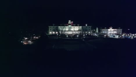 Panoramic-aerial-dolly-along-courtyard-leads-to-historic-colonial-white-hotel-at-night