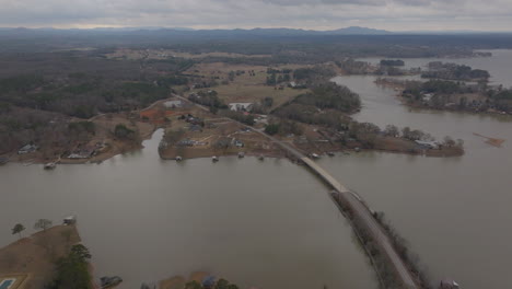 Drone-footage-over-Lincoln,-Alabama,-displaying-lakes,-a-bridge-with-cars,-trees,-and-distant-mountains-during-daytime