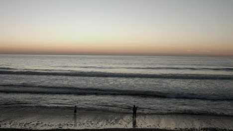 A-family-play-on-the-beach-during-a-sunset-in-Carlsbad,-California-near-San-Diego