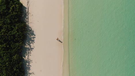 Top-Aufnahme-Von-Touristen,-Die-Auf-Dem-Sand-Des-Strandes-Auf-Der-Insel-Rasdhoo-Auf-Den-Malediven-Spazieren-Gehen