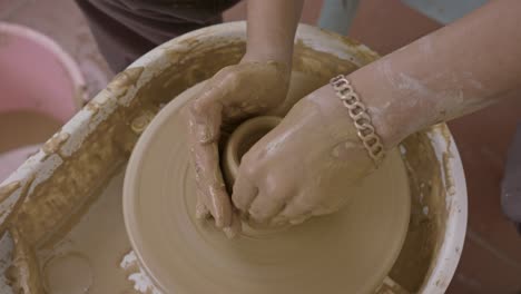 Hands-shaping-clay-on-a-spinning-potter's-wheel,-focus-on-creation,-craftsmanship