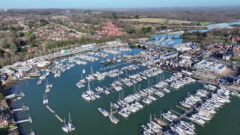 Aerial-shot-flying-over-Hamble-River-boatyard-with-many-yachts,-boats,-bridges,-trains-and-motorway-UK