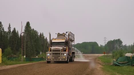 Irrigation-truck-spraying-water-on-rural-road-to-help-country-progress-in-Alberta,-Canada