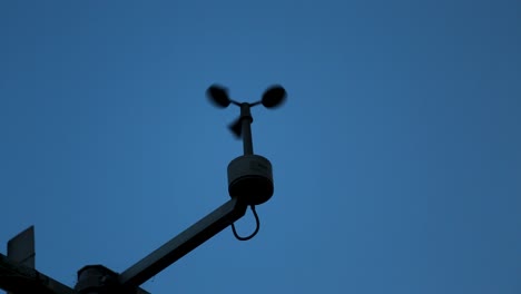 Anemometer-spinning-rapidly-against-a-dusk-sky,-capturing-wind-speed-for-weather-data