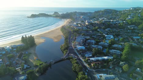 Drone-aerial-landscape-pan-over-Terrigal-beach-suburban-rural-town-with-lagoon-bridge-housing-Central-Coast-travel-tourism-Wamberal-Australia