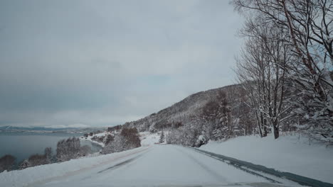 Viaje-En-Primera-Persona-Por-El-Fiordo-Occidental-De-Noruega-En-Un-Día-Nevado-De-Invierno,-Con-Hermosas-Montañas-Y-Carreteras-Nevadas