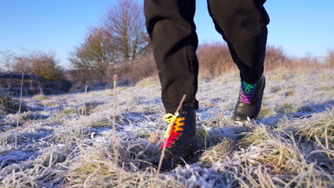 Tracking-shot-boots-walking-through-winter-heavy-frost-grass-in-country-field-4K