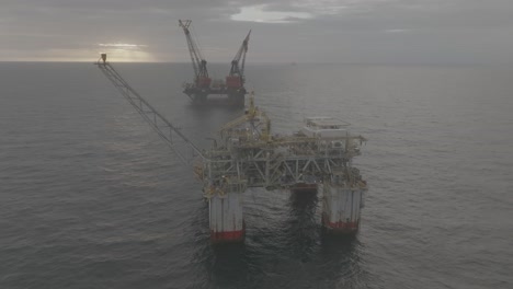 Drone-footage-of-an-offshore-oil-rig-and-a-crane-ship-at-sunrise-on-the-ocean