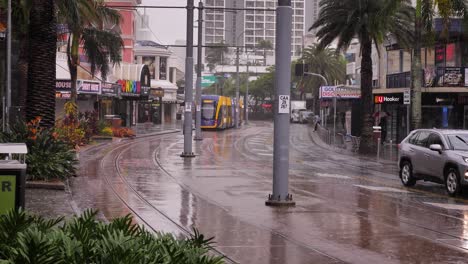 Sehen-Sie-Sich-Eine-Straßenbahn-Und-Ein-Auto-An,-Die-Entlang-Des-Surfers-Paradise-Boulevard-Fahren,-Während-Schwerer-Regen-Und-Stürme-Weiterhin-Die-Goldküste-In-Anhaltenden-Stürmen-Und-Überschwemmungen-Treffen