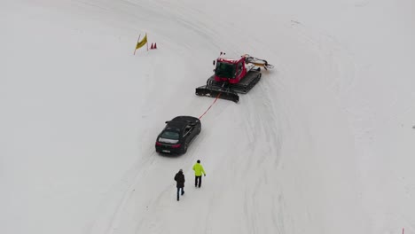 Aerial-view-of-snowcat-heavy-machinery-evacuate-car,-Lungauring-Austria