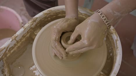 Skilful-potter-deftly-shaping-clay-pot-with-experienced-hands-on-rotating-turntable