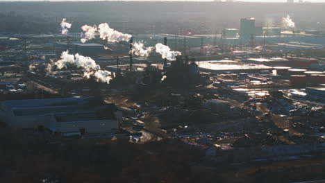 Industrial-complex-with-smokestacks-during-winter,-early-morning-light