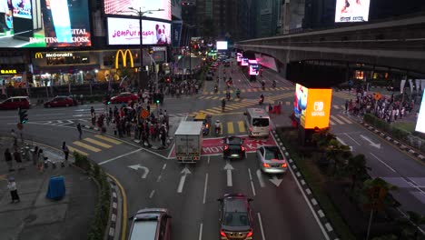 El-Tráfico-Nocturno-Fluye-En-La-Intersección-De-Bukit-Bintang-Con-Peatones-Y-Letreros-De-Neón.