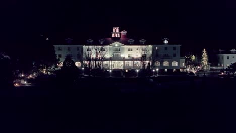 Un-Dron-Se-Eleva-Para-Exhibir-Un-Hotel-De-Estilo-Colonial-Con-Un-árbol-De-Navidad-Iluminado-En-El-Costado-De-La-Entrada.