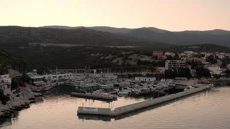 Vista-Panorámica-De-Un-Puerto,-Hora-Dorada,-Balcanes,-Costa-De-Croacia,-Mar-Adriático,-Veleros,-Yates,-Aguas-Tranquilas,-Montañas,-Vista-Del-Amanecer-De-Una-Costa-Rocosa,-Mañana-Tranquila,-Carretera-Junto-Al-Mar