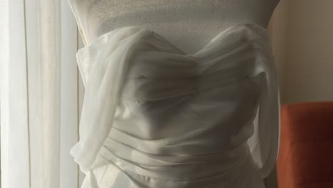 Detail-of-wedding-dress-in-hotel-room-during-bride's-preparation