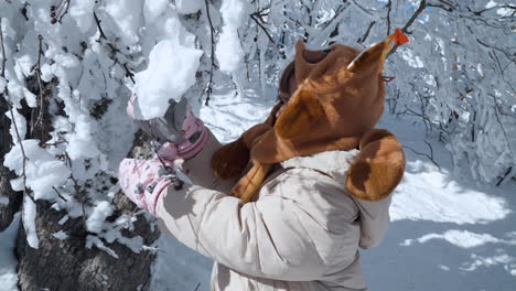 Neugieriges-Kleines-Mädchen-Erkundet-Den-Winterpark-Und-Berührt-In-Zeitlupe-Den-Auf-Ästen-Bedeckten-Schnee---Nahaufnahme