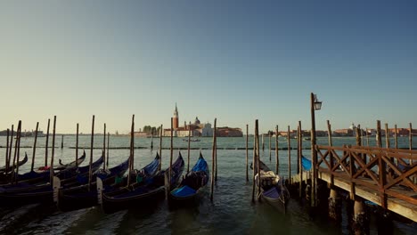 Gondolas,-typical-boats-from-Venice,-moving-on-the-water-in-the-lagoon-near-the-main-square