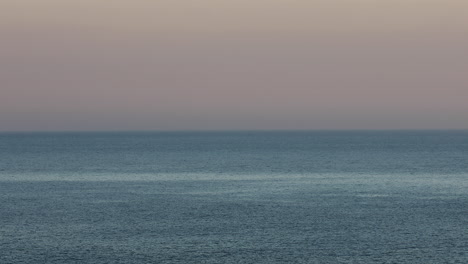 Ruhige-Szene,-Die-Den-Sonnenaufgang-Einfängt-Und-Das-Meer-Nahtlos-Mit-Dem-Himmel-Am-Fernen-Horizont-Verschmilzt