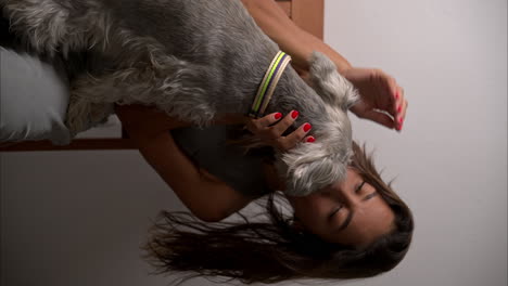 Vertical-Slow-motion-of-a-latin-brunette-model-with-beautiful-eyes-playing-with-her-Schnauzer-dog