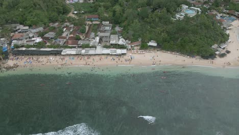 Exotic-sandy-beach-with-many-people-on-warm-cloudy-day,-aerial-view