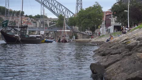 A-shot-capturing-the-Douro-River-and-its-many-cruise-boats,-along-with-people-resting-on-the-river's-shore