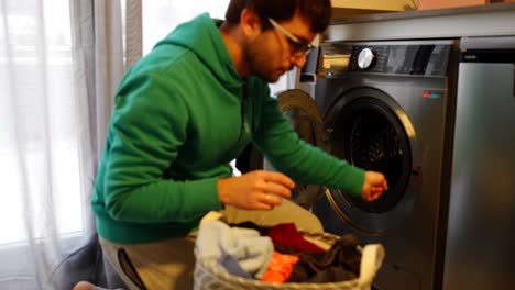 Mann-Beim-Wäschewaschen,-Der-Kleidung-Hinzufügt