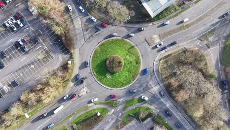 Aerial-birds-eye-view-shot-rising-up-with-car-traffic-around-large-busy-UK-roundabout-4K