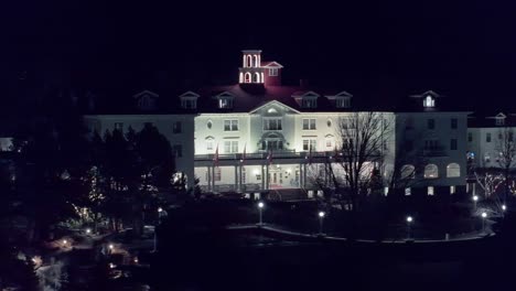 Right-to-left-orbit-around-entrance-to-white-hotel-at-night-with-romantic-walkways-on-grounds