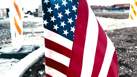 United-States-Flag-waving-in-a-breezy-wind,-construction-site-in-background
