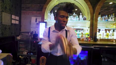 Der-Afroamerikanische-Barkeeper-Verwendet-Ein-Shaker-Tool,-Um-Das-Alkoholische-Getränk-Für-Die-Kunden-Einer-Lokalen-Bar-Zu-Mischen