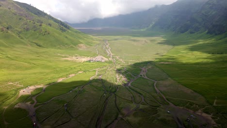 the-transition-from-dry-to-rainy-season-in-this-captivating-aerial-video-of-green-valley-in-Mount-Bromo-the-iconic-active-Volcano,-showcasing-nature's-vibrant-shift-in-hues-and-atmosphere